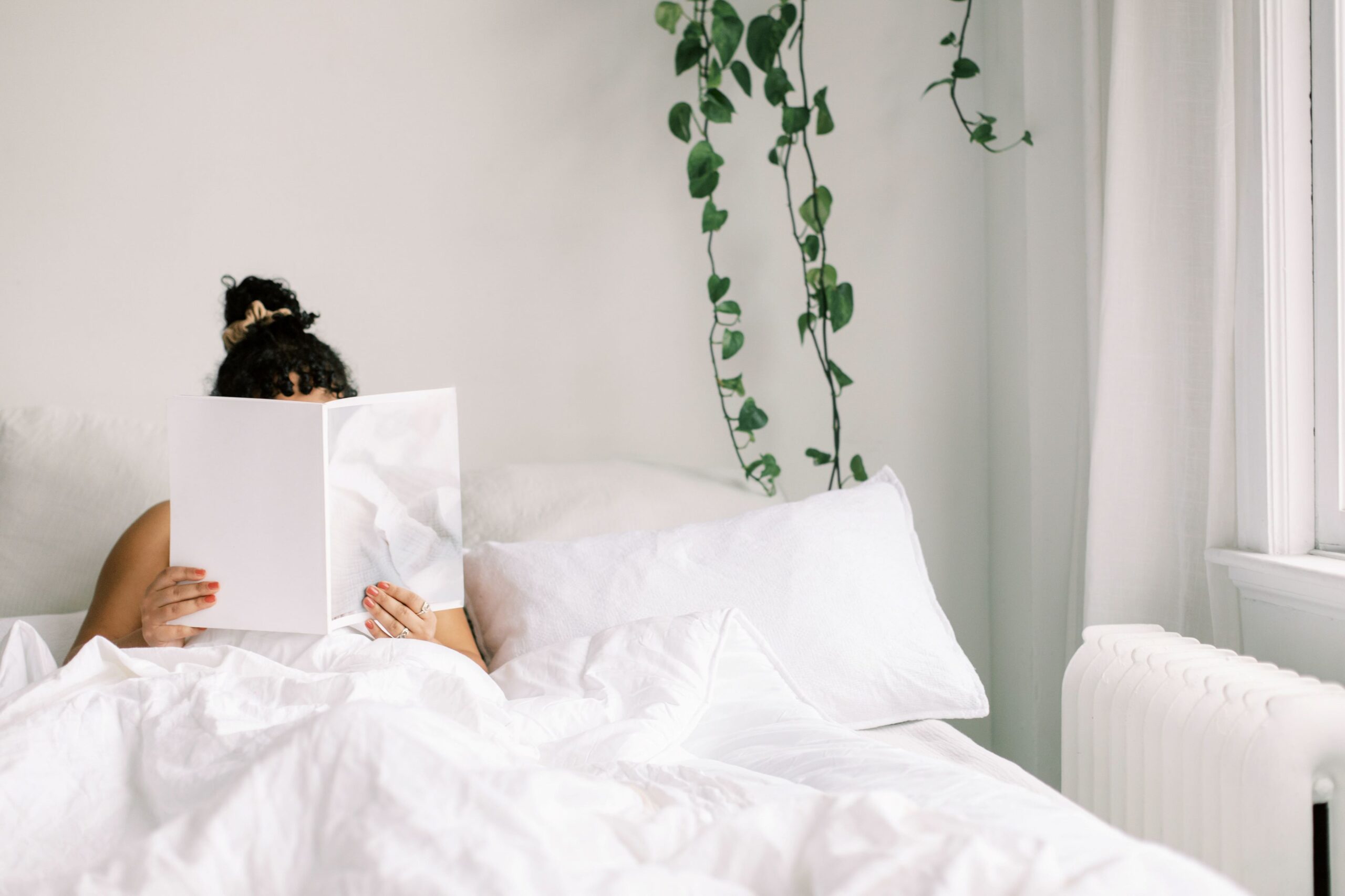 Woman reads while tucked in bed